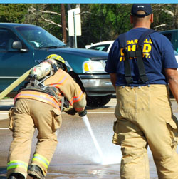 Fire fighter putting all his weight into carrying the charged hose forward.